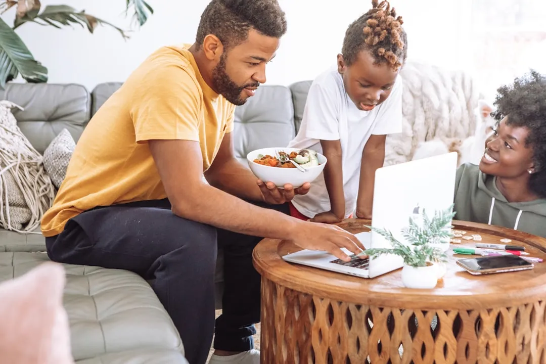 Man in a yellow crew-neck t-shirt sitting on a white couch beside a woman in a white shirt