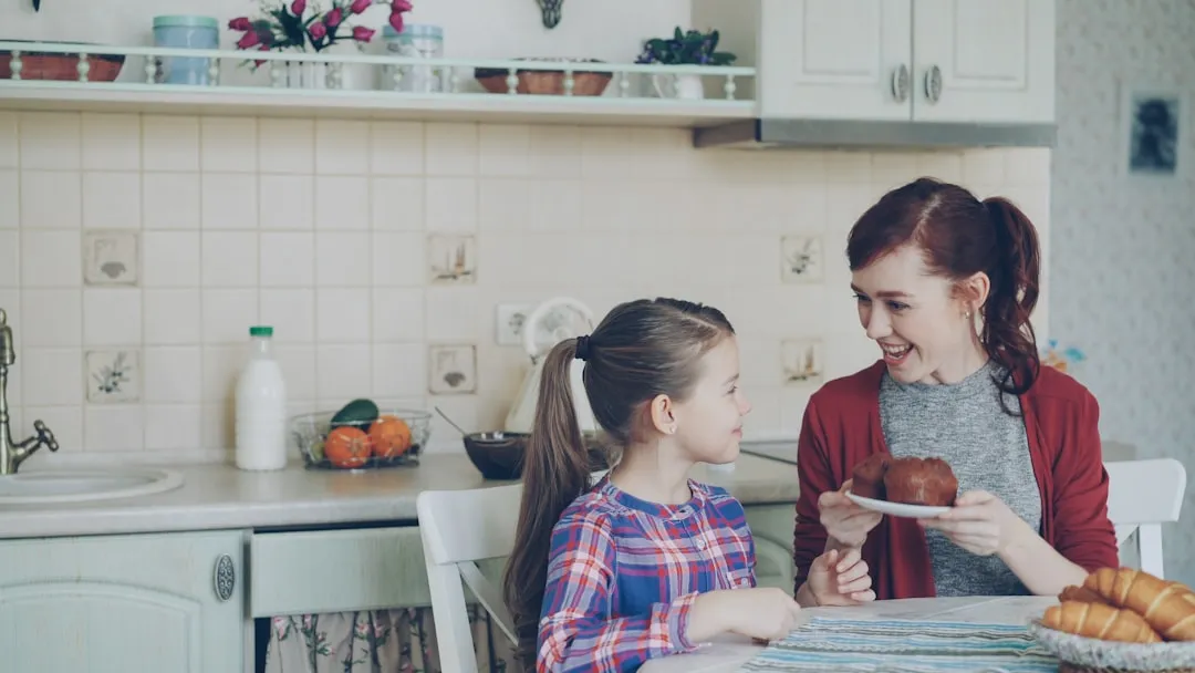 Mother and daughter sharing a treat in the kitchen.