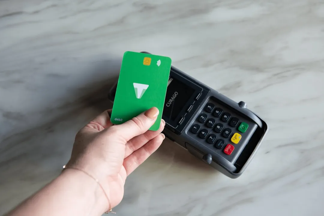 Uma mão segurando um green card ao lado de uma calculadora