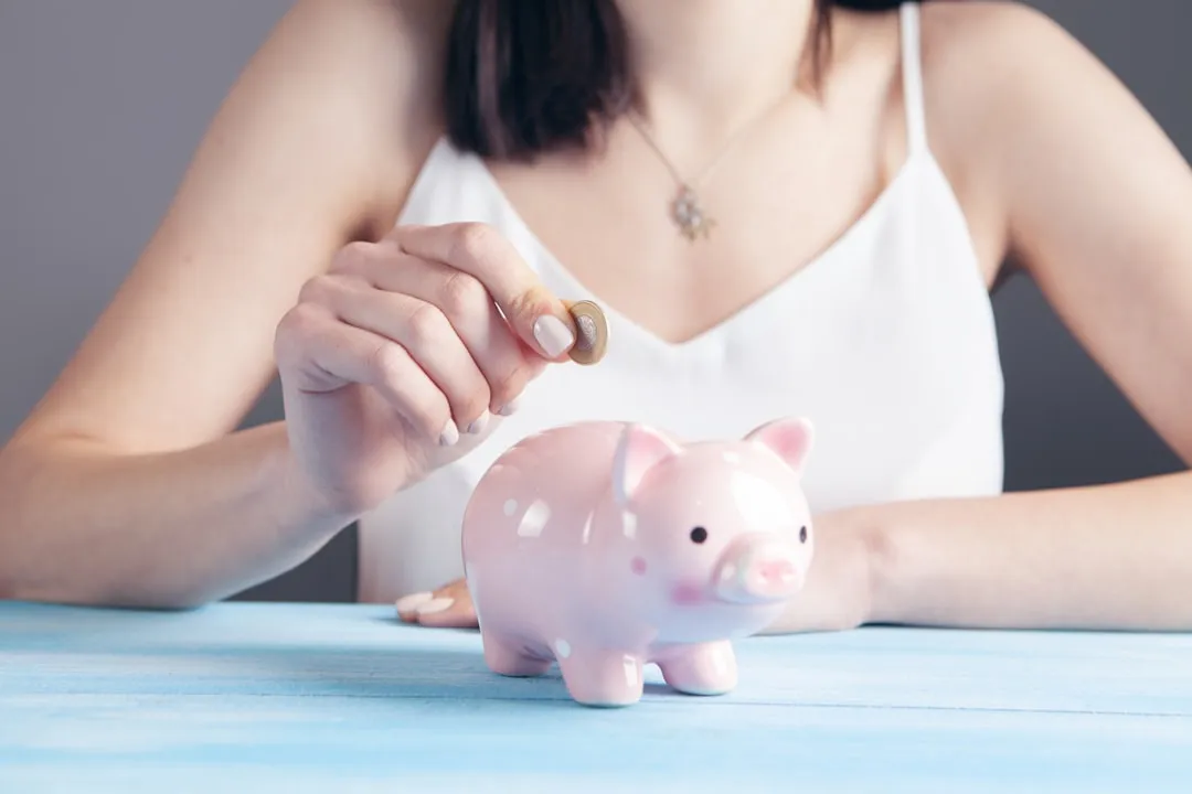 Woman in a white top holding a pink pig figurine