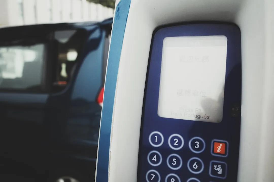 A close-up of a cell phone with a car in the background