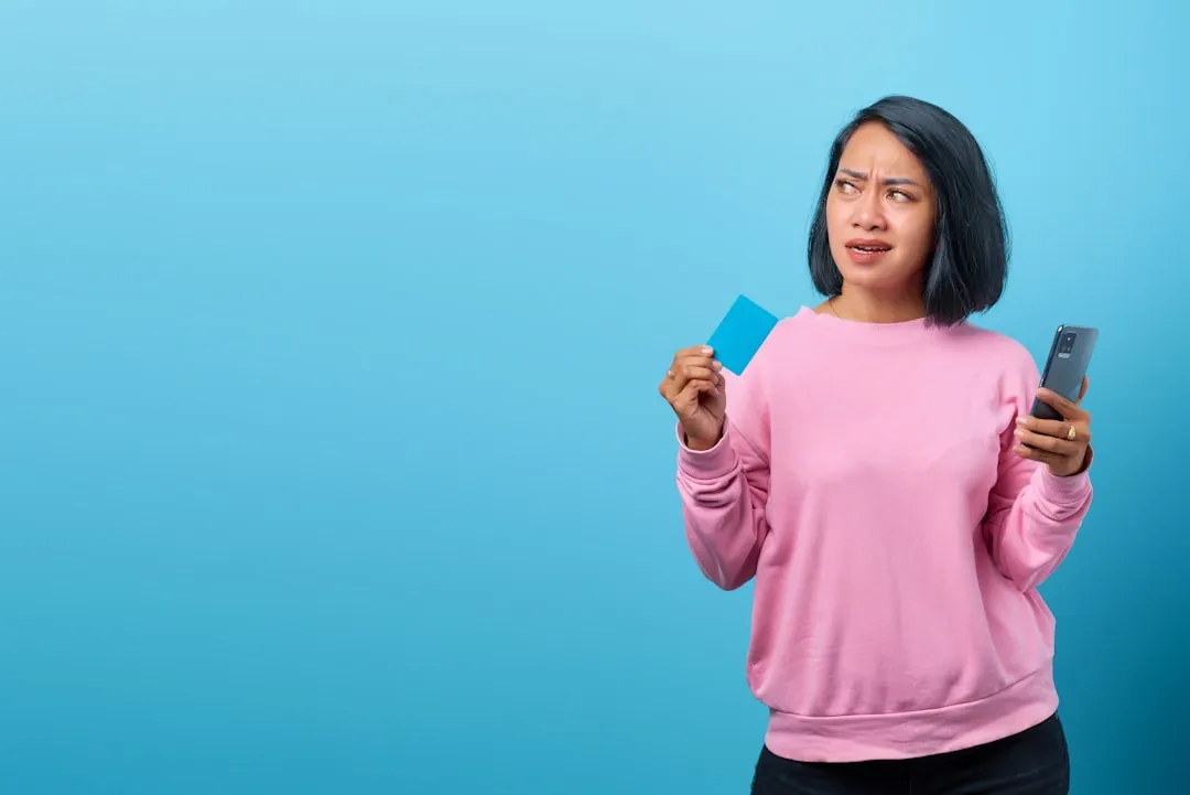 A woman holding a cell phone and a credit card