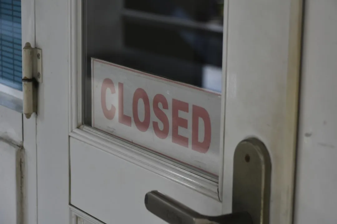 Closed signage on a white wooden half-glass door