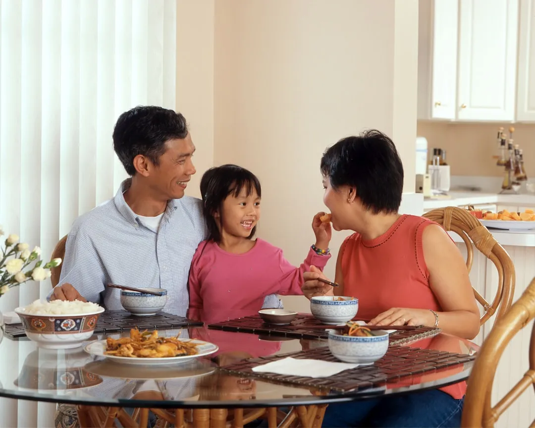 A man, woman, and child sitting at a table eating food