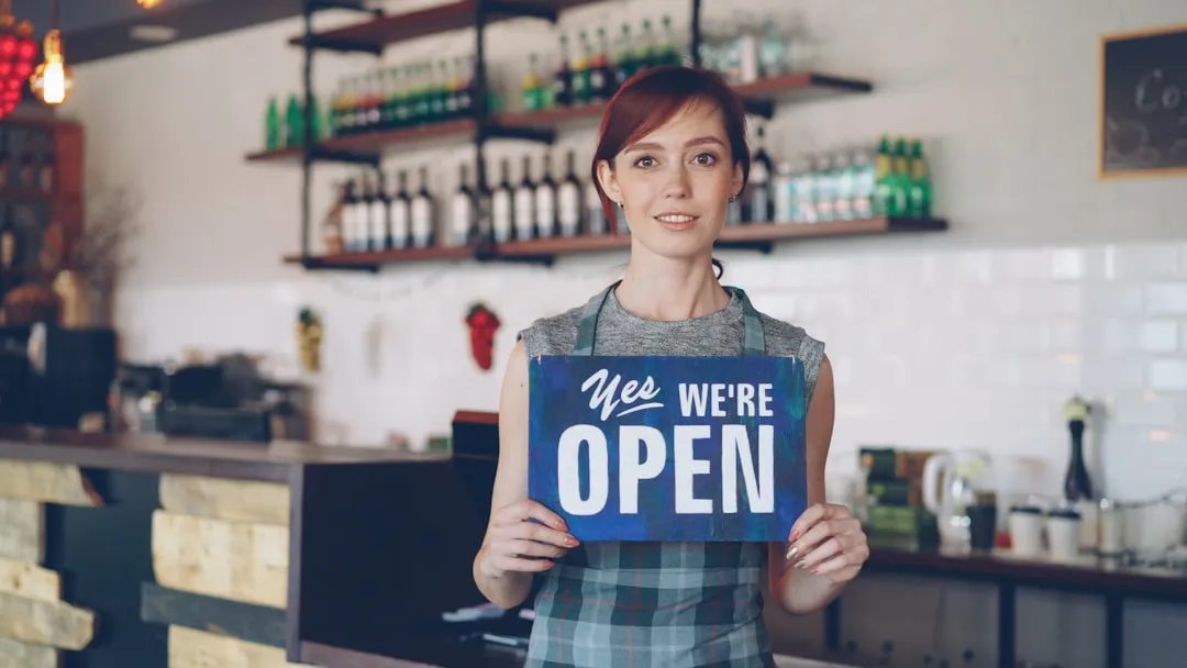 A woman welcomes customers as the shop is open.