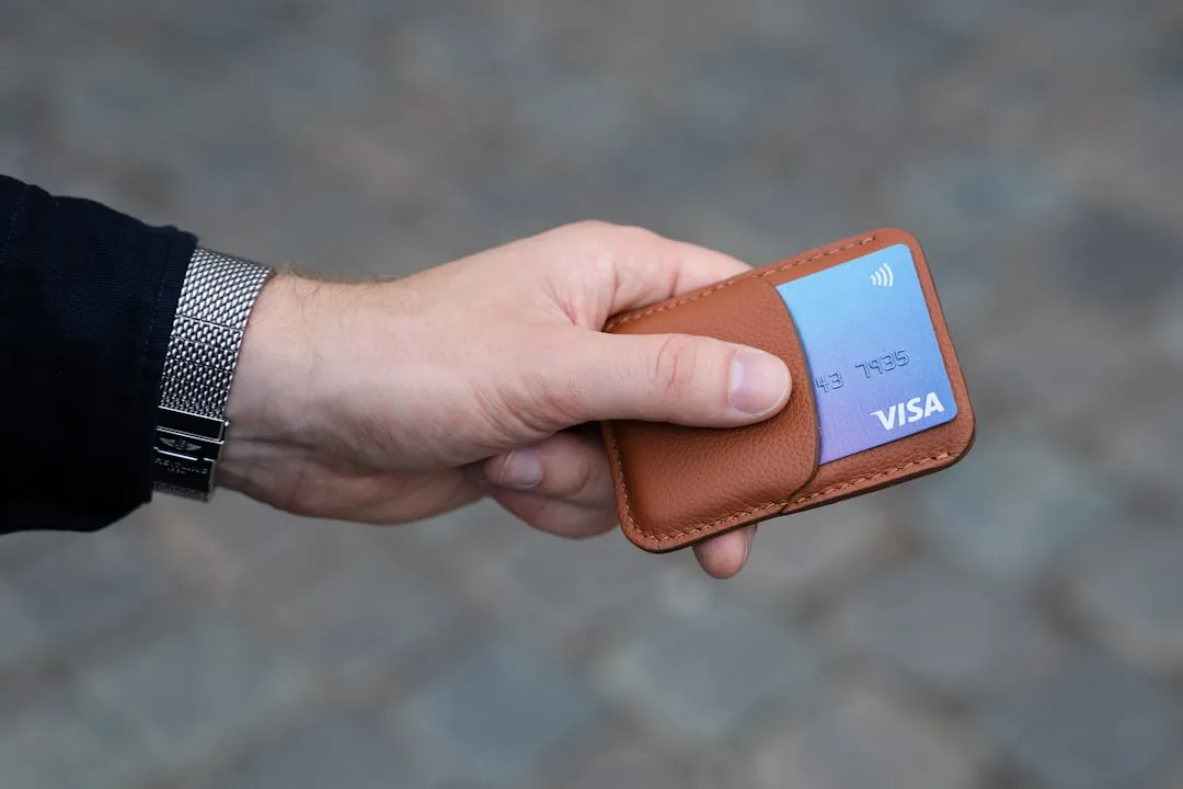 A hand holding a wallet with a credit card A hand holding a wallet with a credit card