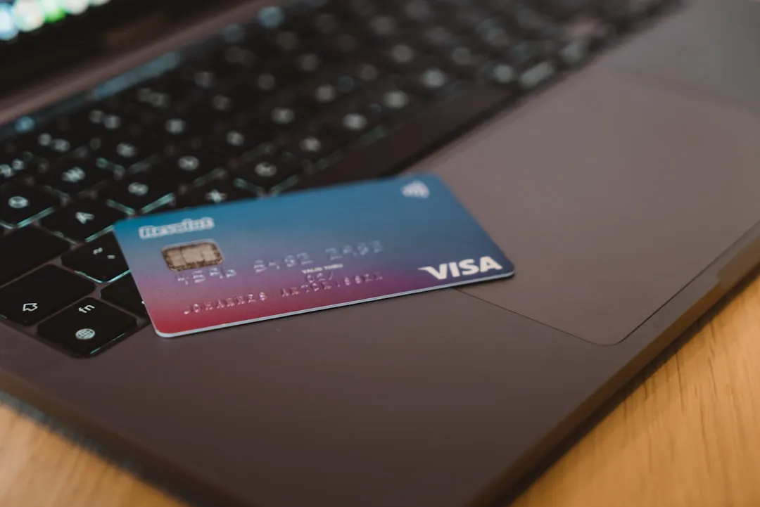 Blue and white Visa card on silver laptop Blue and white Visa card on silver laptop