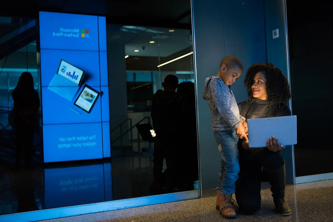 Woman holding a laptop next to a child in a gray jacket