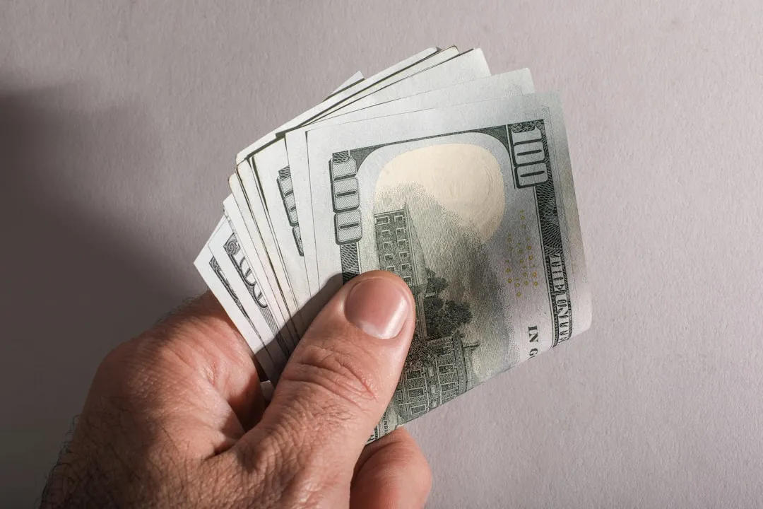 A hand holding a fan of one hundred dollar bills A hand holding a fan of one hundred dollar bills