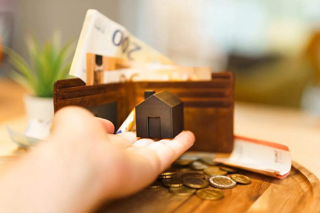 A person holding a small house and some money A person holding a small house and some money
